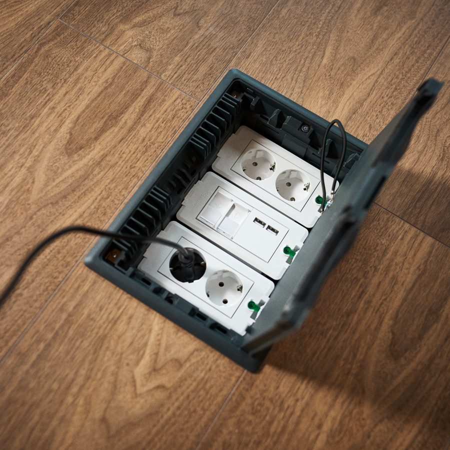 strømuttak i gulv med åpent lokk og tre moduler for vanlig stikkontakt og USB.